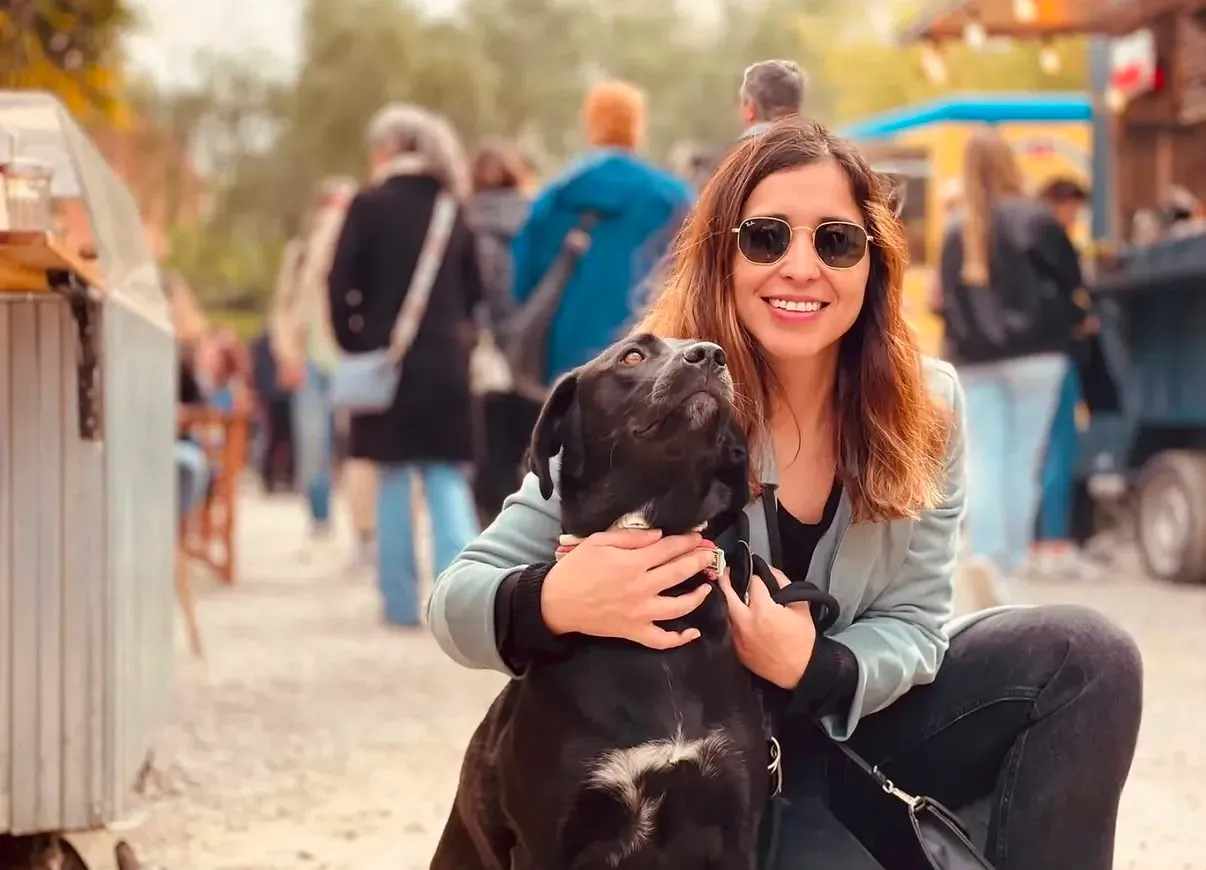Mariana con gafas de sol abrazando a un labrador negro en un mercado al aire libre de Barcelona